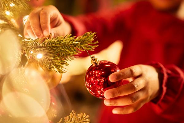 Girl putting Christmas decoration on tree, one of the popular activities during the festive period featuring our article on "festive season meaning explained"